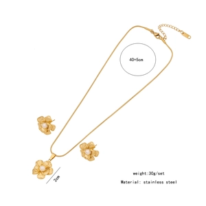 Detail view of gold flower necklace and earrings set with pearls and size measurements