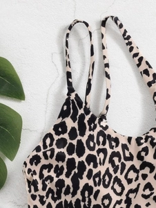 Detailed close-up of leopard print bikini top with thin straps on a textured white surface