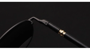 Detailed macro view of black polarized sunglasses temple with polished gold metal hinge