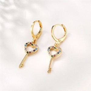 Golden heart key earrings with colorful cubic zirconia stones on white silk background