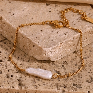 Detailed macro view of 18K gold plated ball chain with baroque pearl on beige stone