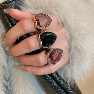 Detailed close-up of three faceted heart-shaped gemstone rings in pink, black, and purple