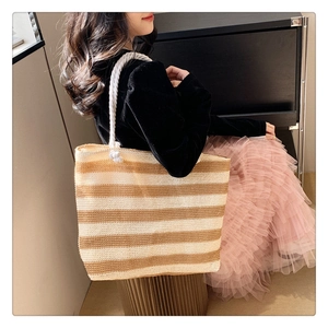 Detail of striped woven tote bag with white rope handles and natural texture