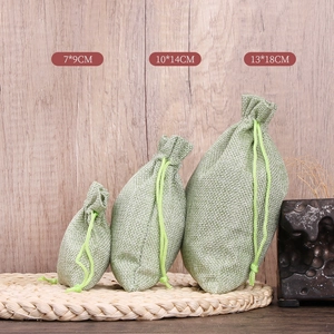 Three sizes of green drawstring linen jewelry pouches shown on a wooden background