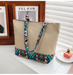 Close-up of beige canvas tote bag with vibrant geometric tribal pattern on straps and base
