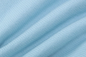 Detailed macro view of soft light blue knitted wool fabric with a fine textured weave