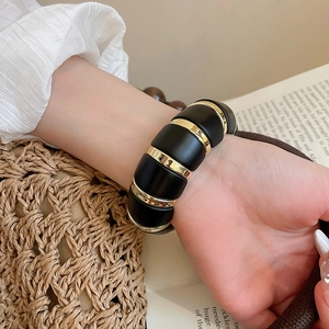 Chic black and gold acrylic segmented elastic bracelet worn by model in elegant setting