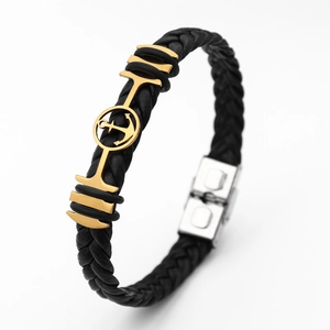 Detail of black braided leather bracelet with gold anchor and silver magnetic clasp