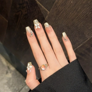 Detail of champagne gold glitter nails with 3D white flower petals and small pearls