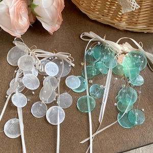 Detail view of round shell tassel earrings with white silk bows and hanging pearls