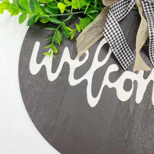 Close-up of wooden welcome sign with linen bow and realistic artificial greenery detail