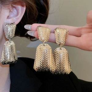 Close-up of golden geometric diamond earrings with a unique woven texture pattern