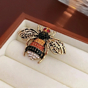 Macro shot of bee brooch with colorful crystals in a beige velvet jewelry box