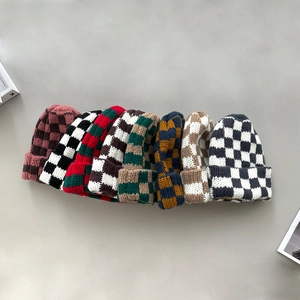 Detail view showing an array of checkered knitted beanies in multiple autumn colorways
