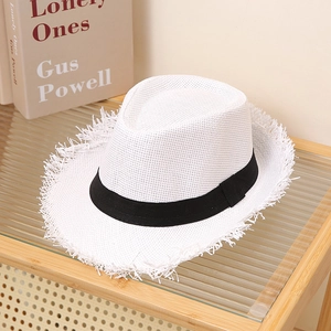 Detailed close-up of white straw hat featuring frayed brim edges and a black ribbon band