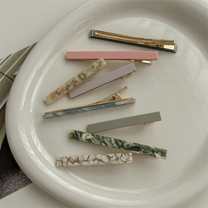 Set of 8 acetate hair clips in assorted marble and solid colors on a ceramic tray