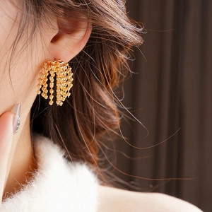 Close-up of gold-plated fireworks tassel earrings with multi-strand beads on a model