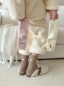 Detail of warm plush socks with cute animal embroidery in pink, beige and brown tones