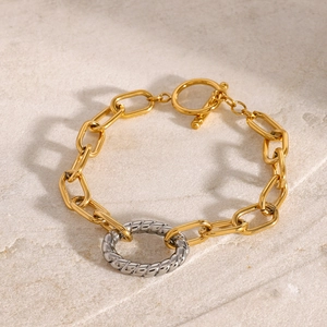 Close-up of gold oval link bracelet with silver twisted ring and T-bar toggle clasp