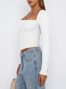 Detail view of a white long sleeve crop top with a square neckline and elastic fabric
