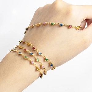 Gold stainless steel chain bracelet with multi-colored heart pendants on model wrist