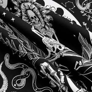 Detail shot of gothic tapestry fabric showing skull, snake, and moon print texture