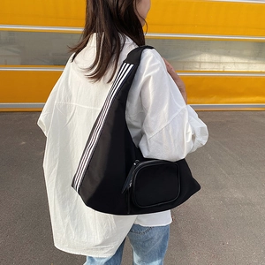 Minimalist black nylon shoulder bag with white stripes and side pocket for women