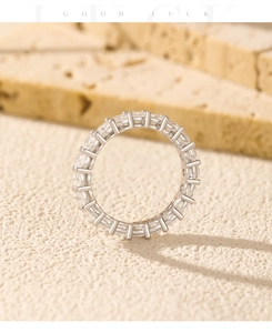 Macro detail of silver S925 eternity ring with round moissanite stones on travertine base