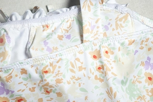 Detailed view of floral pattern and fine stitching on white deep V-neck dress strap