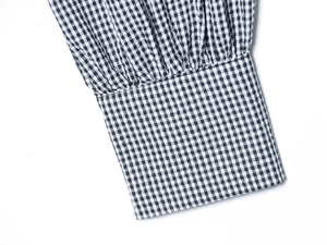 Detailed macro view of navy blue gingham check shirt cuff with fine pleated stitching