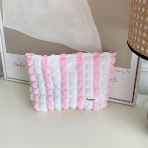 Macro detail of pink seersucker striped makeup bag showing puffy texture and Sozakka label