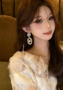 Detailed close-up of a model wearing elegant white pearl geometric drop earrings
