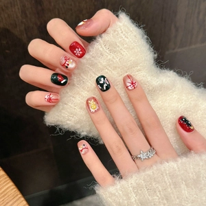 Handmade Christmas press-on nails featuring red and green festive art with bow and snowflake
