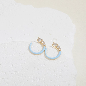 Detail view of light blue enamel C-shaped earrings with gradient zircon inlays on stone
