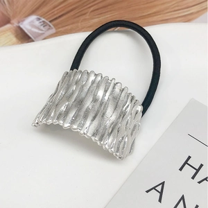 Close-up of silver metal hair tie with wave texture on a minimalist black elastic band
