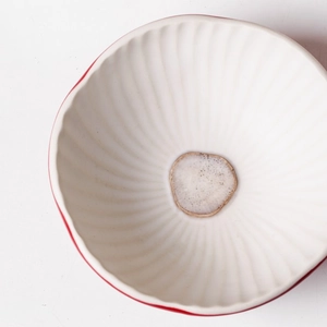 Detail shot of a cute red mushroom ceramic bowl with wavy texture and smooth inner glaze