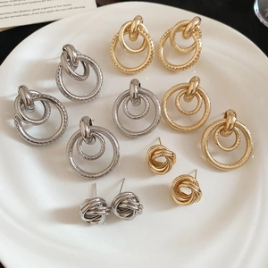 Détail de boucles d'oreilles torsadées et de pendentifs circulaires en métal doré et argenté