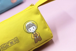 Dettaglio dell'astuccio in tela gialla con stampa di astronauta e manico resistente
