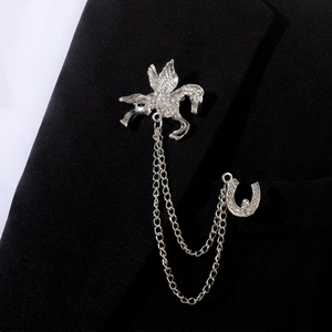 Détail de la broche col pégase et fer à cheval argentée avec chaîne sur veste noire