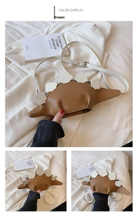 Detail view of brown dinosaur-shaped shoulder bag featuring decorative white back plates