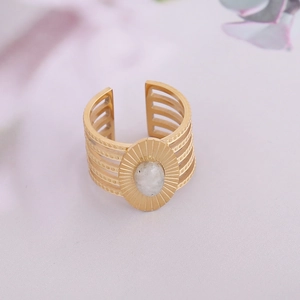 Détail d'une bague dorée ornée d'une pierre de marbre ovale et texture de soleil