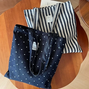 Détails de sacs fourre-tout en denim à pois et rayures bleues sur une table en bois