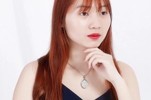 Silver necklace with an oval sparkling rhinestone pendant worn by a model on a black top