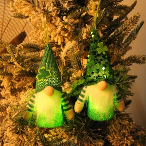 Light-up St. Patrick's Day gnomes with green clover hats hanging on a snowy tree