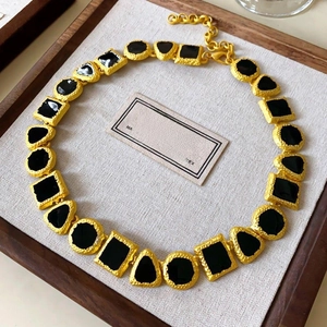 Detail of vintage gold necklace with black geometric stones on beige jewelry display