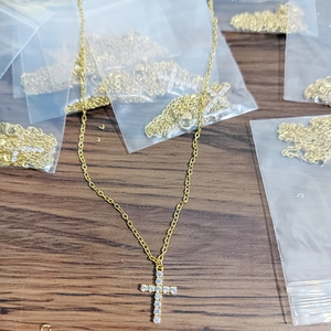 Detailed view of 18K gold plated cross necklace with tiny CZ stones on wood surface