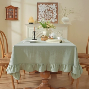 Detail of light green washed cotton tablecloth with elegant ruffled edges on a table