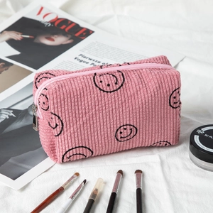 Detail of pink corduroy makeup bag with black smiley face print and silver metal zipper