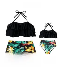 Detail of ruffled halter bikini top and high-waisted tropical palm leaf print bottoms