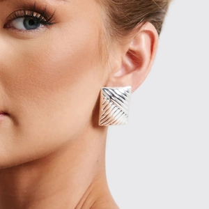 Silver rectangular textured stud earrings with diagonal pattern on female model ear